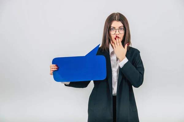 Retrato de una joven mujer de negocios emocionada sosteniendo una burbuja vacía de habla azul cuadrada, cubriéndose la boca con la mano, cara sorprendida . —  Fotos de Stock