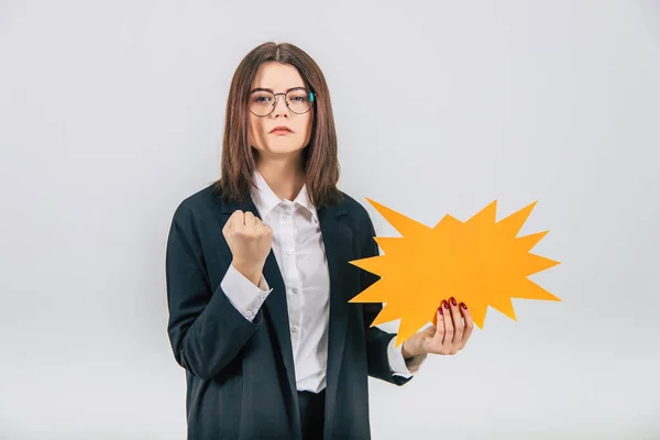 Excited young business woman holding an empty sparkle-like speech bubble, clenching her fists, looking angry. — Stock Photo, Image