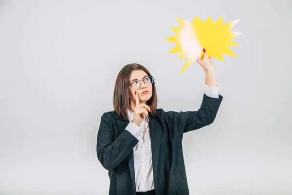 Portrait of an excited young business woman raising up empty sparkle-like speech bubble, looking at it, thinking, keeping her finger on the cheek. — Stock Photo, Image