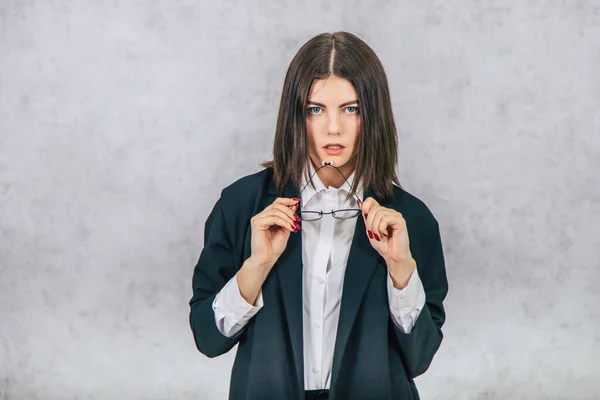 Femme d'affaires sérieuse tenant ses lunettes, regardant avec séduction et confiance la caméra . — Photo