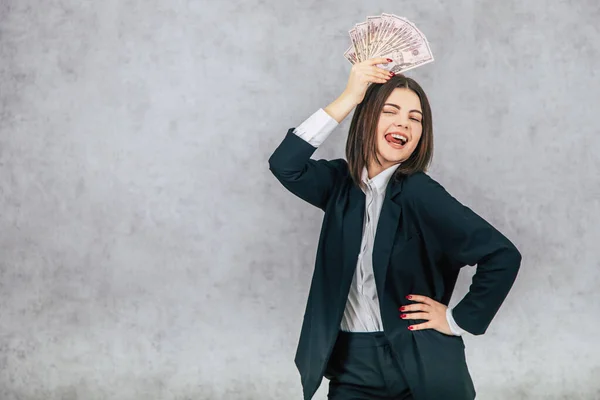 Jeune femme d'affaires extrêmement heureuse, posant, tenant un ventilateur de billets d'argent au-dessus de sa tête, tenant la main akimbo . — Photo