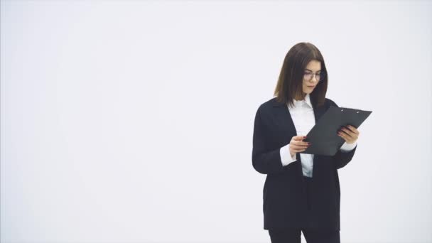 Longitud completa de atractiva mujer de negocios en traje de pie con el titular de papel en sus manos, comprobando los datos, mirando a la cámara, sonriendo . — Vídeos de Stock