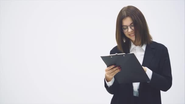 Takım elbiseli çekici bir iş kadını elinde kağıt tutucuyla okuduklarından etkilenmiş bir şekilde verileri kontrol ediyor.. — Stok video