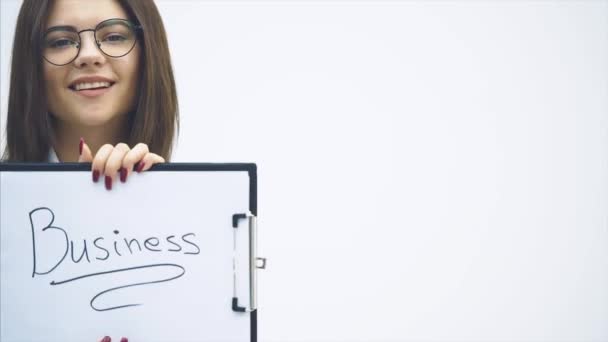 Donna d'affari ispirata in abito nero in piedi con appunti in mano, girandolo verso la fotocamera, sorridendo. La parola "affari" è scritta sul foglio di carta . — Video Stock