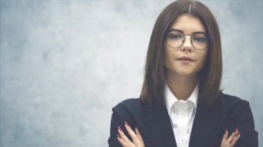 Siyah takım elbiseli hoş bir iş kadını kollarını kavuşturup kameraya bakıyor..