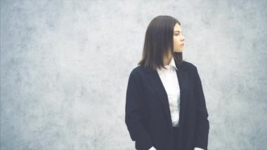 Siyah takım elbiseli genç bir kadın kalabalıkta birini arıyor, sonra da selam veriyor..