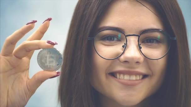 Gehakt gezicht van een lachende jonge zakenvrouw in een formeel zwart pak met een zilveren munt. Focus op de munt op de voorgrond. — Stockvideo