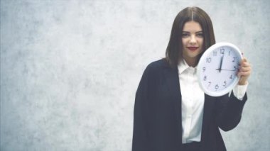 Siyah takım elbiseli komik genç iş kadını, saati kaldırıyor, komik bir şekilde ellerini sallıyor, dans ediyor, dudağını büküyor..