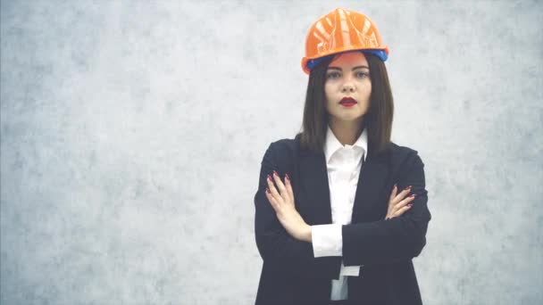 Hermosa joven arquitecta en casco y traje mirando a la cámara, posando, con las manos dobladas . — Vídeos de Stock