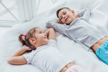 İki tatlı çocuk rahat bir kanepede uzanmış, ellerini başının üstüne koyup uyumaya hazırlanıyorlar..