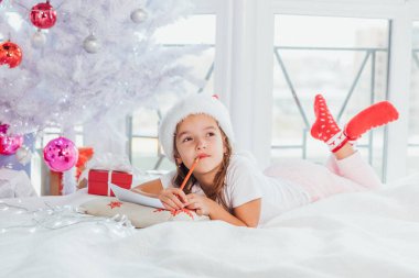 Yoğunlaşmış çocuk, tüm isteklerini ve arzularını düşünüp Noel Baba 'ya mektup yazıyor..