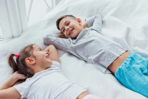 Dos dulces niños tumbados en un acogedor sofá, con las manos sobre la cabeza, listos para tomar una siesta . — Foto de Stock