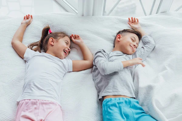 Dos dulces niños tumbados en un acogedor sofá, con las manos sobre la cabeza, listos para tomar una siesta . — Foto de Stock