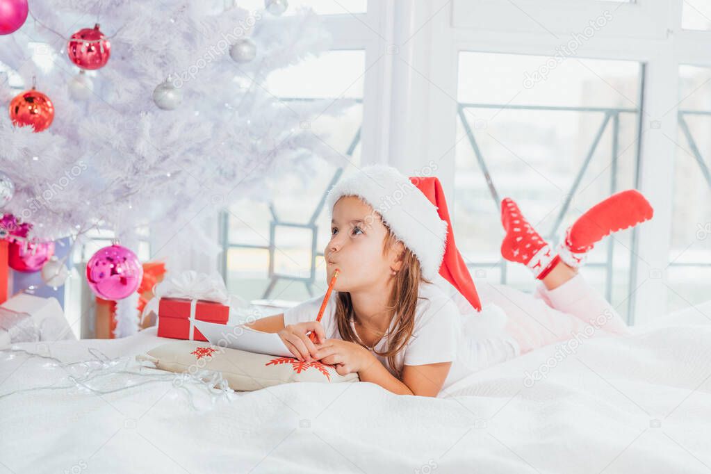 Concentrated kid is involved inthe process of thinking over all her wishes and desires, writing a letter to Santa.