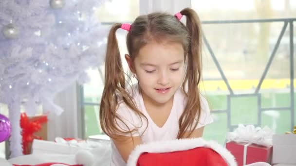 Красива дитина в капелюсі Санта і дивиться на камеру, посміхаючись, як ангел . — стокове відео