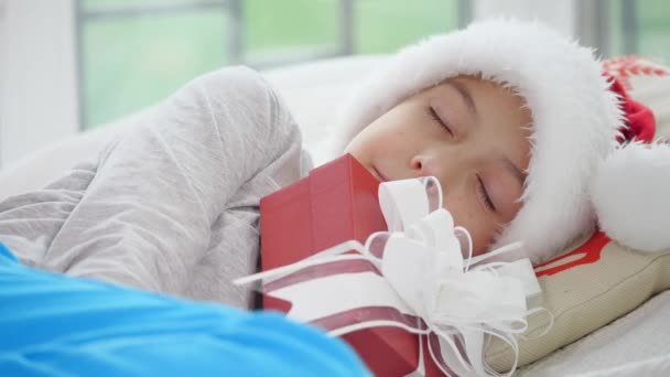 Jolie vidéo de petit garçon en chapeau de Père Noël, dormant avec cadeau de Noël . — Video