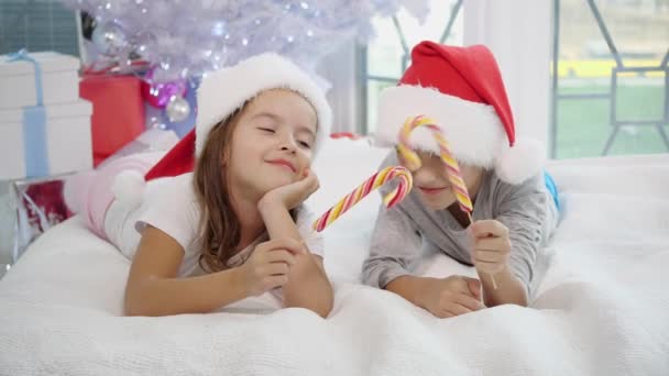 Ζεστή ατμόσφαιρα Χριστουγέννων στην οποία χαρούμενη αδελφή και ο αδελφός παίζει με καραμέλα μπαστούνια, μιμούμενοι μια ξιφομαχία. Τα γλυκά των αδελφών σπάνε και άρχισε να κλαίει.. — Αρχείο Βίντεο