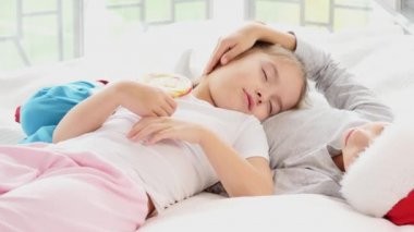 Çekici kız kardeşi ağabeyinin karnında uyuyor. Çubukta lolipop tutuyor. İkisi de çok tatlı görünüyor..