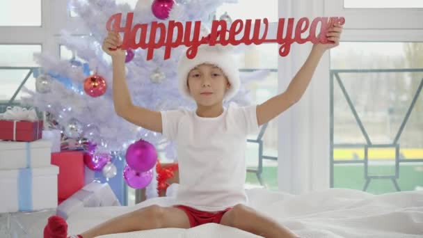 Lustiger flippiger Junge hebt roten Frohes Neues Jahr Schriftzug in die Höhe. — Stockvideo