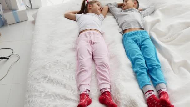 Deux enfants doux couchés sur un canapé confortable, les mains sur la tête, prêts à faire une sieste . — Video