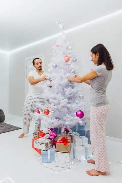 Rodziny, x-mas, ferie zimowe i koncepcja ludzie - szczęśliwa para dekorowanie choinki z piłką w domu — Zdjęcie stockowe