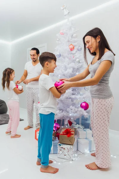 Joven hermosa familia decora el árbol de Navidad — Foto de Stock