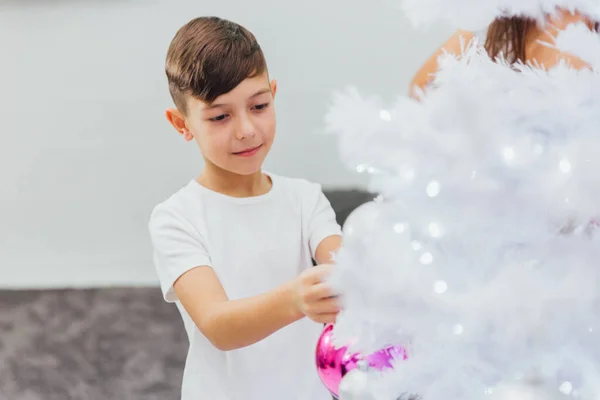 Rapaz bonito decorar árvore de Natal com contas violetas — Fotografia de Stock