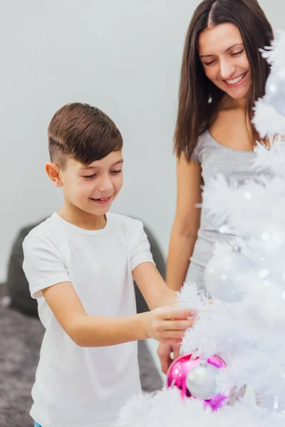 Cenas de Natal da vida real: mulher e seu filho decoram uma árvore de Natal com brinquedos festivos — Fotografia de Stock