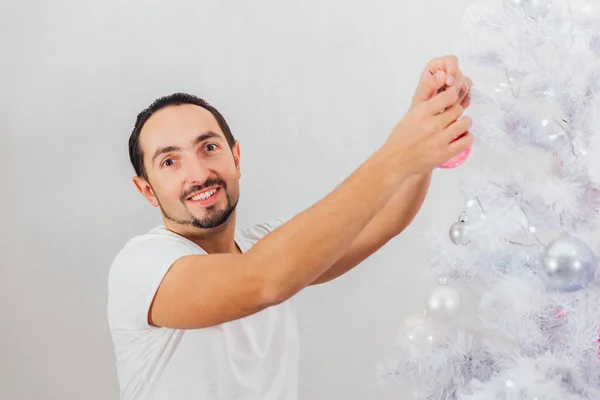 En man klär upp en julgran med leksaker — Stockfoto