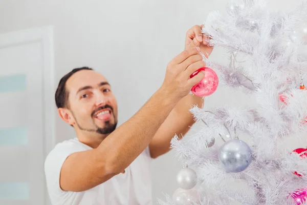 Ένας άντρας ντύνεται Χριστουγεννιάτικο δέντρο με παιχνίδια. — Φωτογραφία Αρχείου