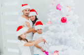 Krásná rodina tráví svůj dobrý čas jako rodina na den vánoc tím, že zdobí obrovský vánoční stromeček, vánoční téma