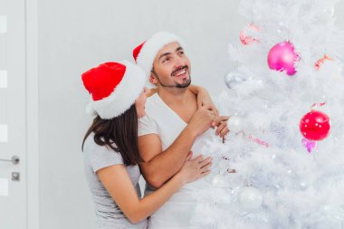 Güzel romantik çift, bir Noel ağacını iç salonda süslüyor.