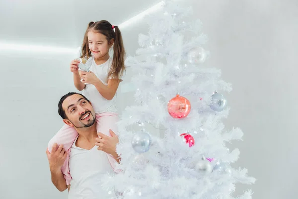 Гордий тато допомагає своїй маленькій дівчинці прикрасити ялинку вдома — стокове фото