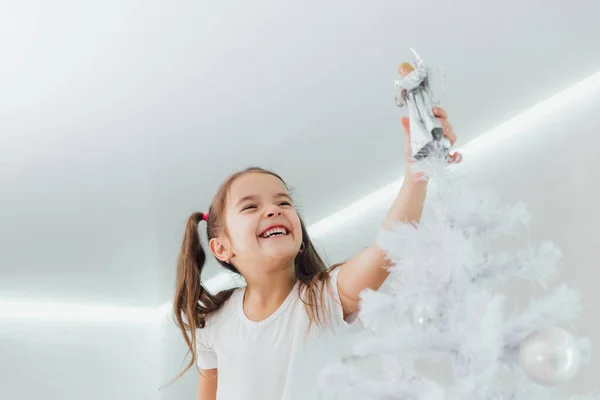 Lachendes Mädchen setzt silbernen Engel an den Weihnachtsbaum — Stockfoto