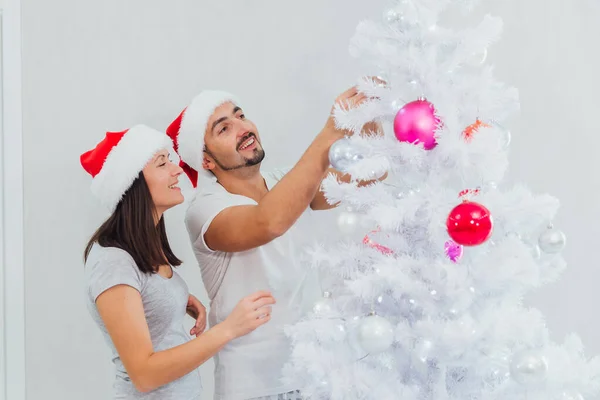 Φωτογραφία ενός νεαρού ευτυχισμένου ζευγαριού να στολίζει ένα χριστουγεννιάτικο δέντρο — Φωτογραφία Αρχείου