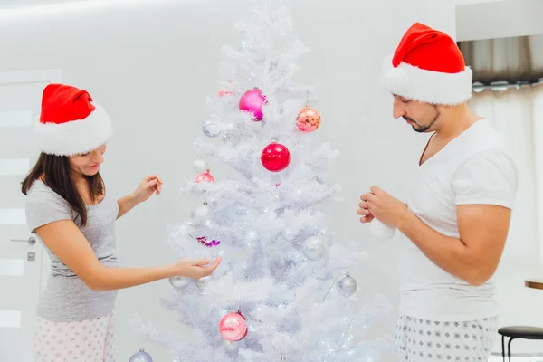 Χριστουγεννιάτικο δέντρο διακόσμηση νεαρό ζευγάρι βάζοντας σε μπάλες Χριστούγεννα σε λευκό δέντρο μαζί — Φωτογραφία Αρχείου