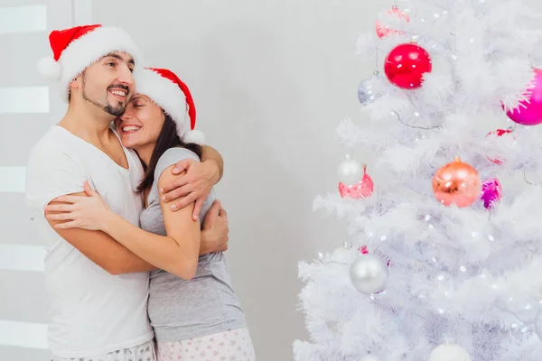 Οικογένεια, x-mas, χειμερινές διακοπές και άνθρωποι της έννοιας - ευτυχισμένο ζευγάρι αγκαλιάζει κοντά στο χριστουγεννιάτικο δέντρο στο σπίτι — Φωτογραφία Αρχείου
