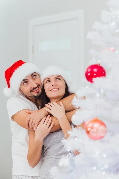 Νεαρό ευτυχισμένο ζευγάρι κοντά σε ένα χριστουγεννιάτικο δέντρο — Φωτογραφία Αρχείου