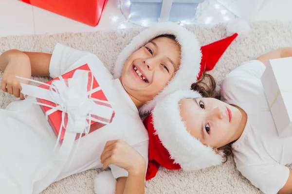 Enfants heureux tenant des cadeaux de Noël et couchés sur le sol — Photo