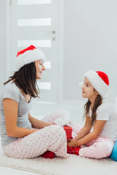Свята, подарунки, різдвяні, різдвяні концепції - щаслива мати і дитина в капелюхах Санта помічника з подарунковою коробкою — стокове фото