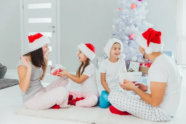 Pais felizes e crianças trocando presentes perto da árvore de Natal em casa — Fotografia de Stock