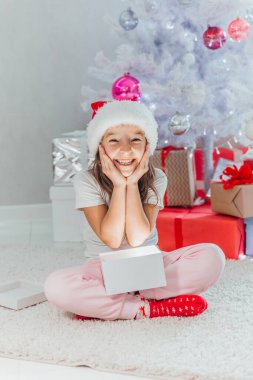 Mutlu Noel ağacı yanında otururken bir büyülü parlak Noel hediyesi kız açar