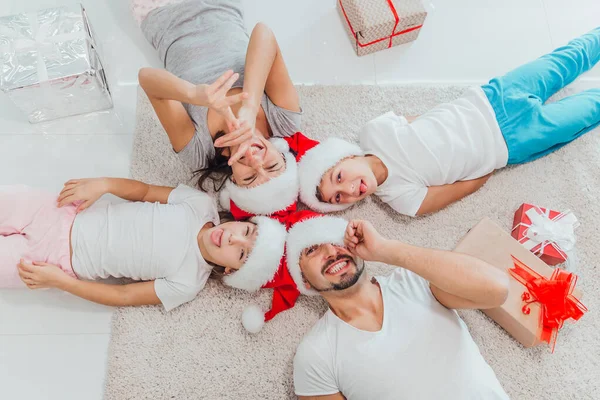 Щаслива сім'я лежить на килимі біля чудових різдвяних подарунків. Радісно бути разом у Новий рік. угорі — стокове фото