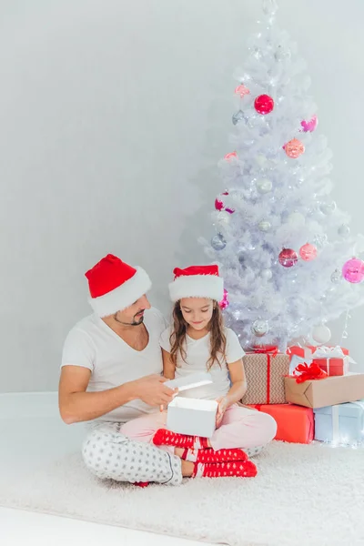 Förvånad lilla dotter öppna en julklapp med sin far hemma — Stockfoto