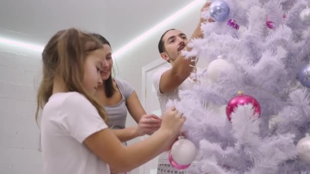Video van een familie die een kerstboom versiert met kleurrijke boubles in de woonkamer. — Stockvideo