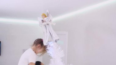 Yakışıklı baba kızını omuzlarına alır, kızı gülümser ve Noel ağacının tepesinden bir melek indirir..