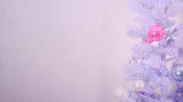 Kerstboom versierd met wit zilver en roze tinten is stralend met bloemenslingers op witte achtergrond. — Stockvideo