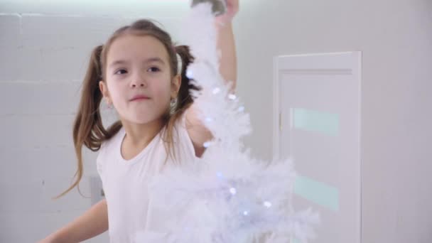 Dolce bambina è desiderosa di raggiungere una decorazione angelo sulla cima dell'albero di Natale . — Video Stock