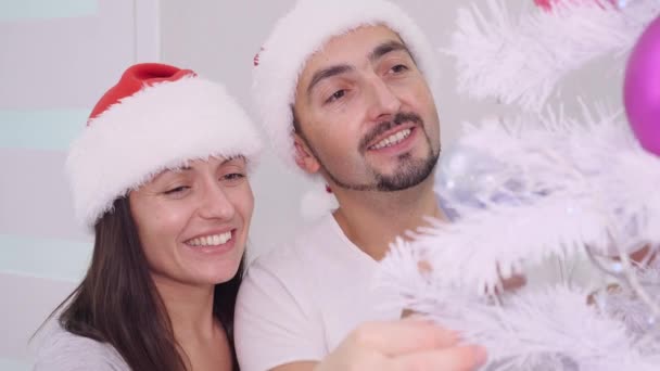 Primer plano de la alegre pareja disfrutando de las vacaciones de invierno, cerca del árbol de Navidad, sonriendo y abrazándose . — Vídeos de Stock