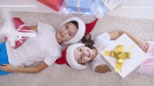 Niños complacidos mostrando sus regalos, mirando a la cámara, sonriendo . — Vídeos de Stock